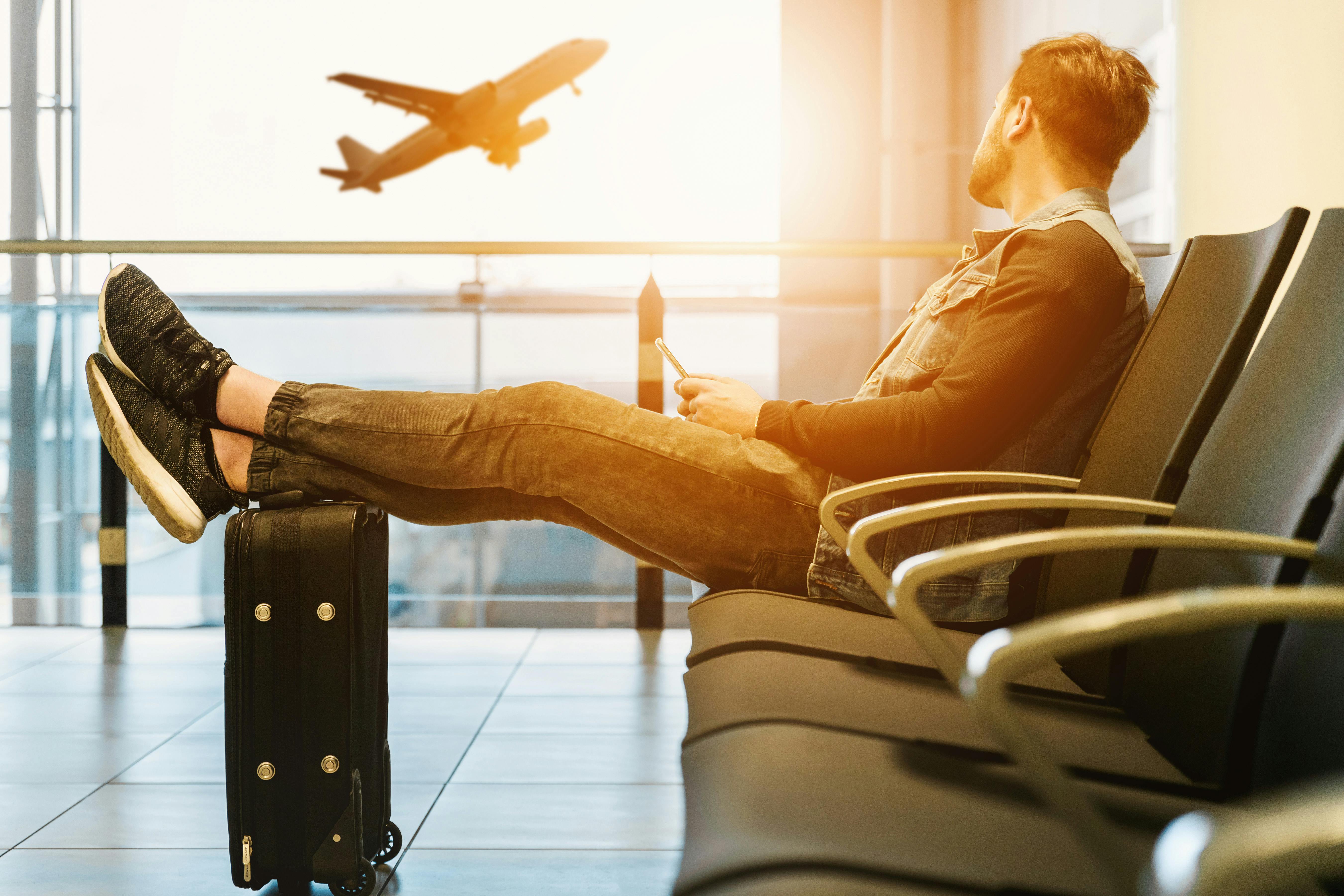 Traveler waiting at airport gate with plane taking off